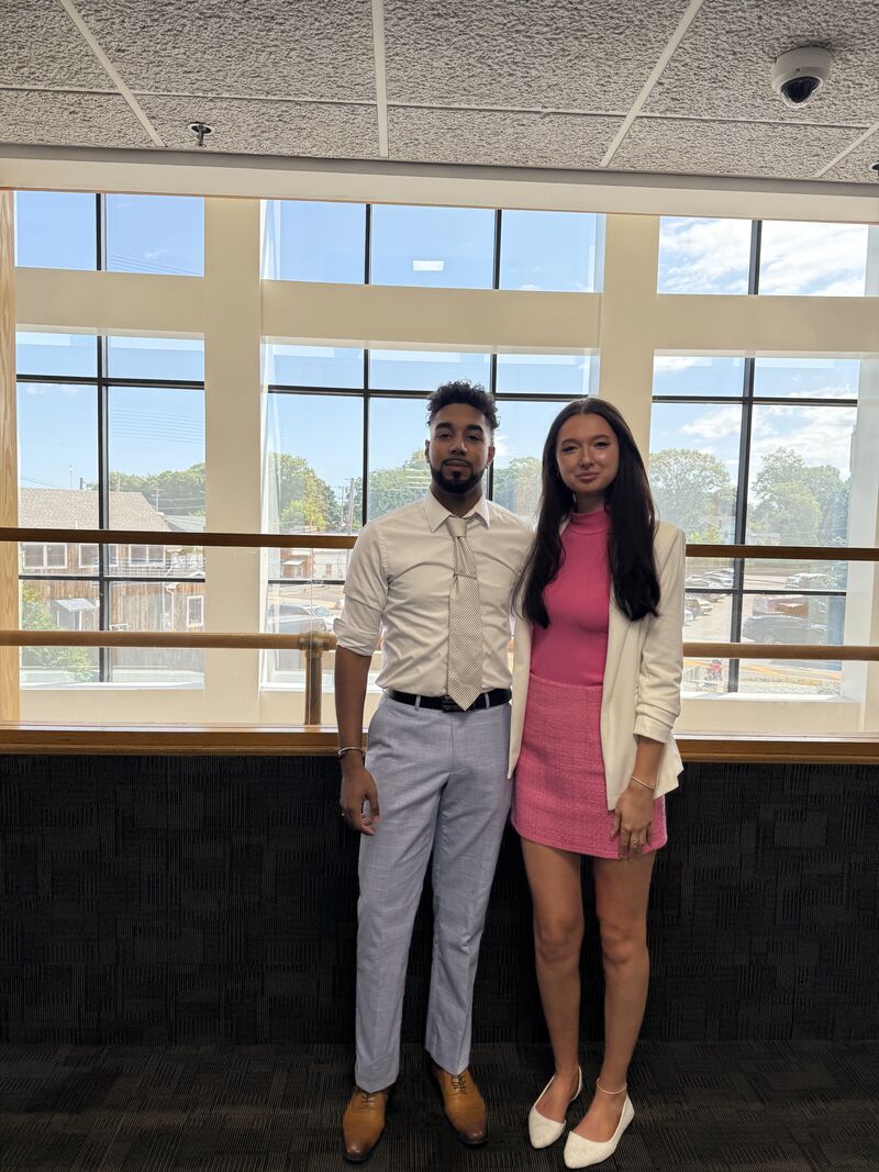 Two professionally dressed representatives standing by a bright window